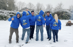 The PlowWow team outside in the snow wearing branded blue PlowWow hoodies